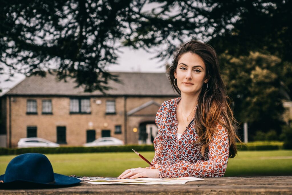 A brunette woman with long hair paints outdoors in a Dublin park, exuding creativity.