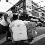 Black and white image of a street vendor pushing a cart in bustling Manila.