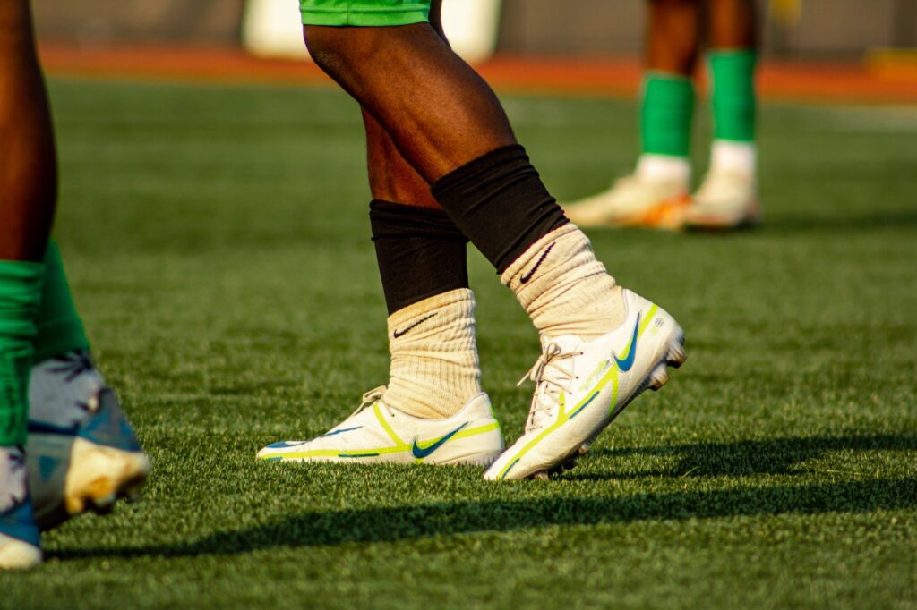 Soccer players training on a grass field in bright cleats and socks.