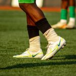 Soccer players training on a grass field in bright cleats and socks.