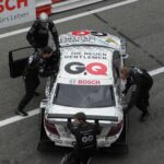 A racing team pushes a Mercedes-Benz race car on the track at Zandvoort.