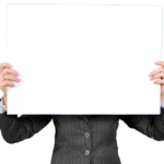 An individual in a formal blazer holds a blank whiteboard, ideal for custom messages.