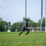 A young soccer player in action on a sunny day in New York City park.
