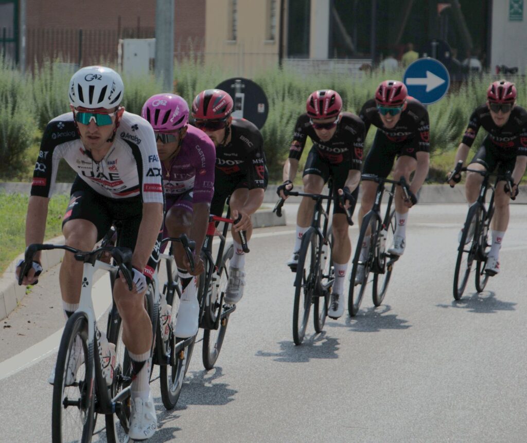 Cyclists in a competitive road race wearing colorful jerseys and helmets.