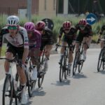 Cyclists in a competitive road race wearing colorful jerseys and helmets.