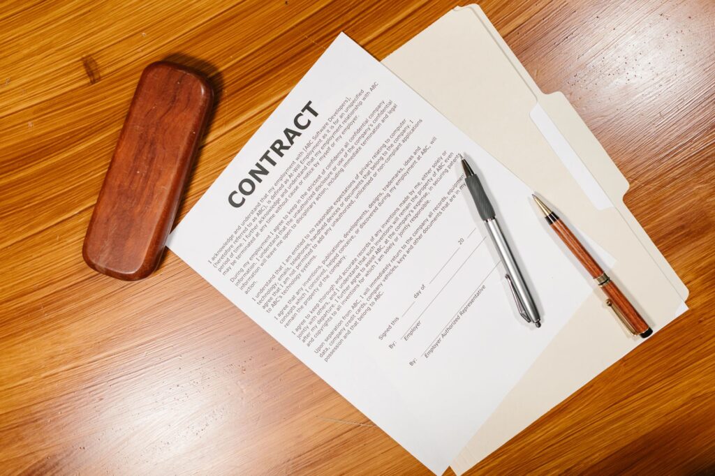 High-angle view of a contract document with pens and a case on a wooden table.
