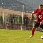 A soccer player in action on a sunny day at a field in Rajec, Slovakia.