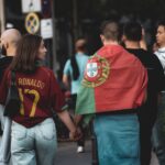 A group of football fans in Berlin, one wearing a Portugal flag, walking the street.