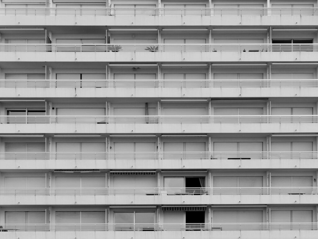 A black and white view of a symmetrical high-rise apartment building with closed shutters.