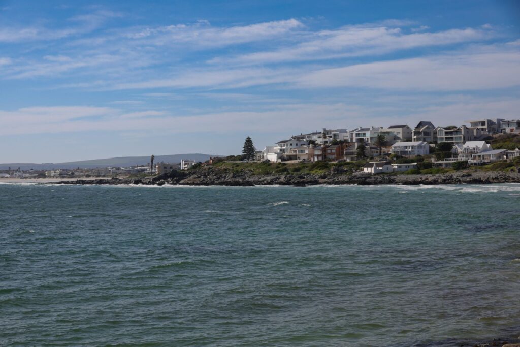 Picturesque coastline with ocean waves and coastal houses under a clear blue sky.