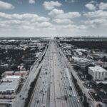 Aerial view of a bustling urban highway with vehicles and buildings, capturing city life and transportation.