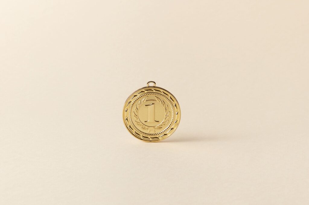 Close-up of a gold medal with '1' displayed on a sleek beige backdrop.