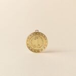 Close-up of a gold medal with '1' displayed on a sleek beige backdrop.