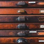 Vintage brown wooden cabinet with thin drawers decorated with cozy creative handles of different shape in craftsmanship